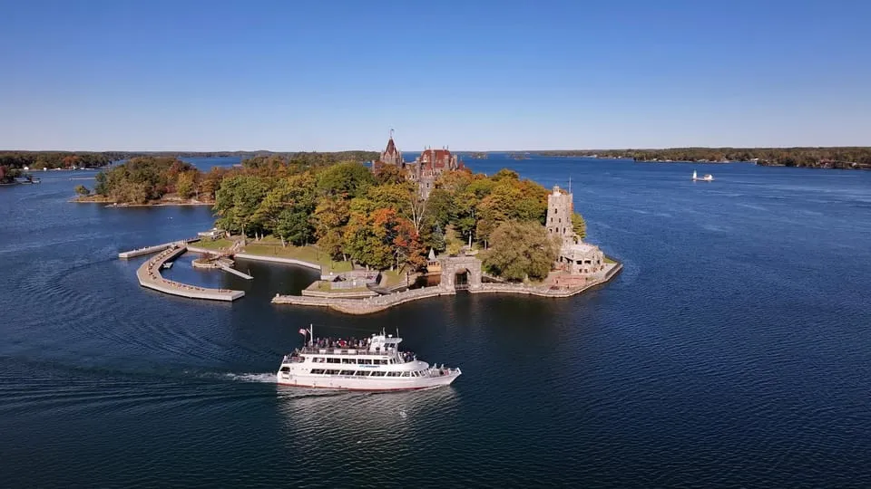 Cruise boat passing forested islands and Boldt Castle on a Gananoque boat tour of the 1000 Islands on the St. Lawrence River